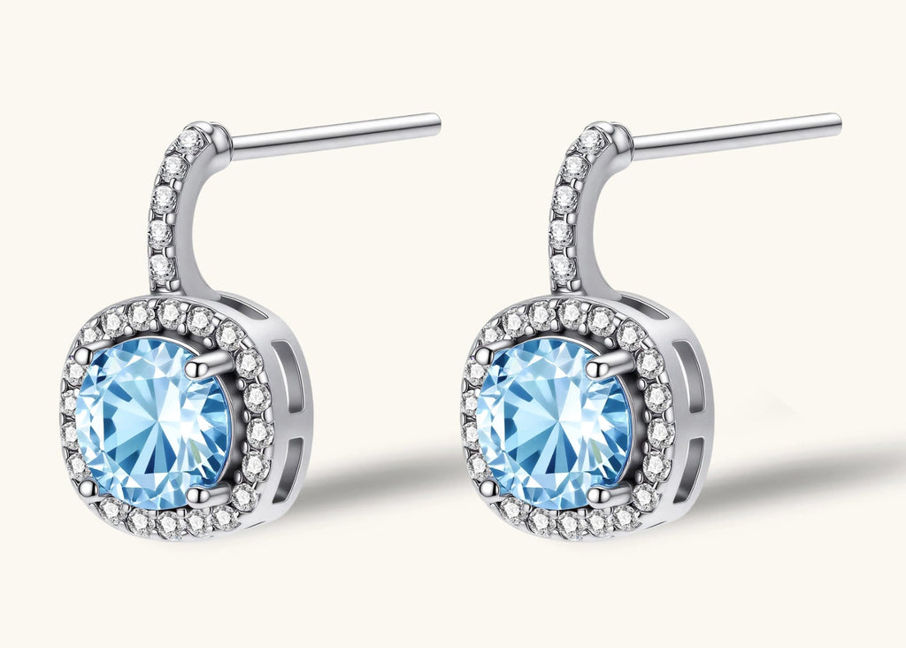 Sterling silver drop earrings featuring cushion-cut blue moissanite stones surrounded by sparkling halo settings
