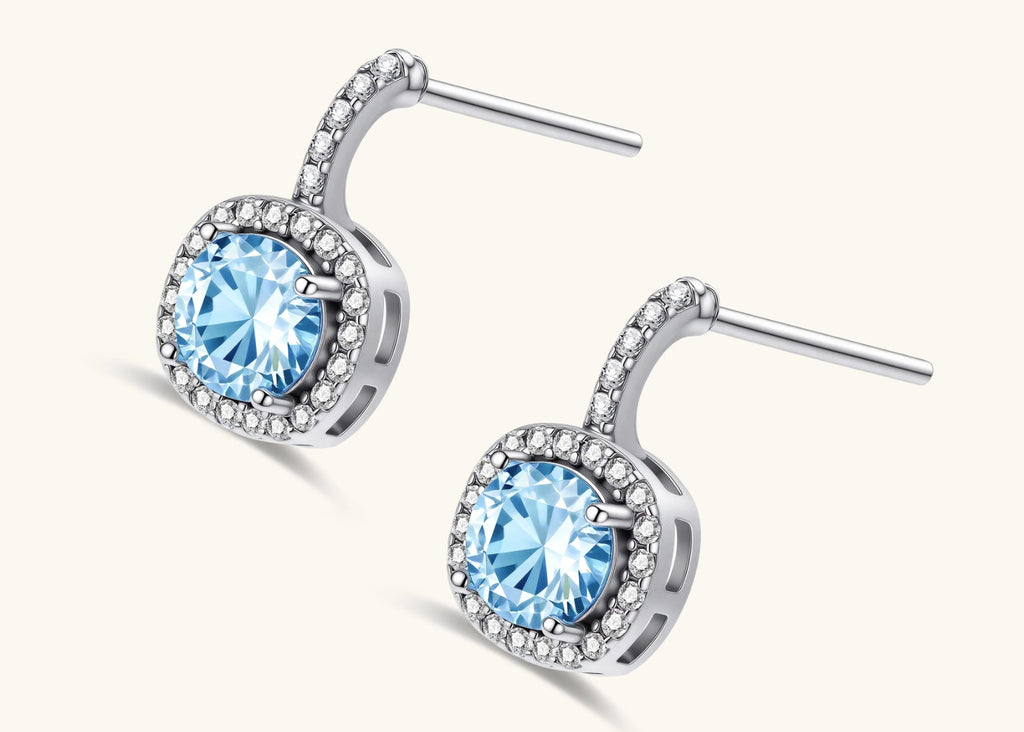 Sterling silver drop earrings featuring cushion-cut blue moissanite stones surrounded by sparkling halo settings